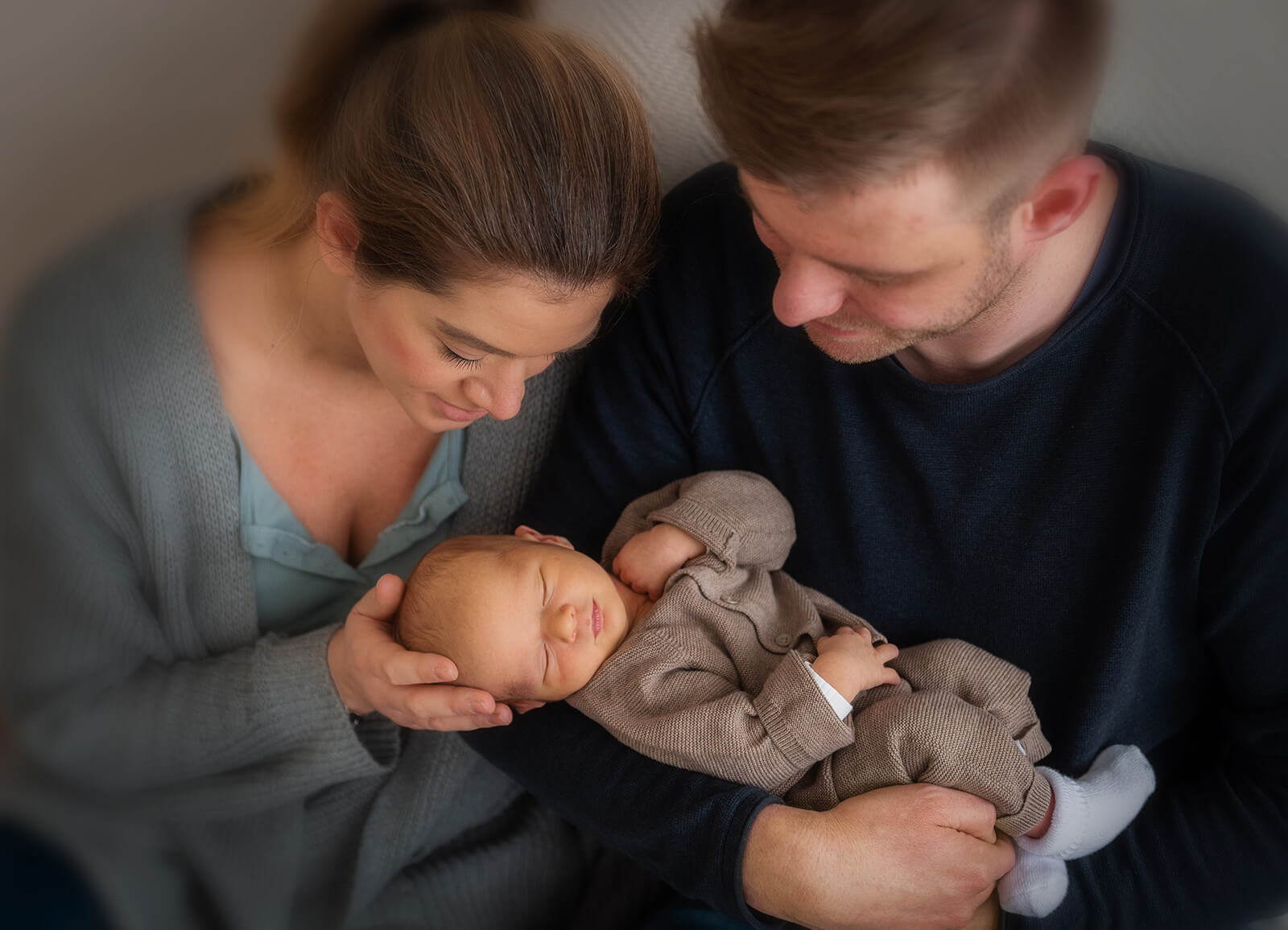 frisch gebackene Eltern schauen liebevoll ihr Baby an