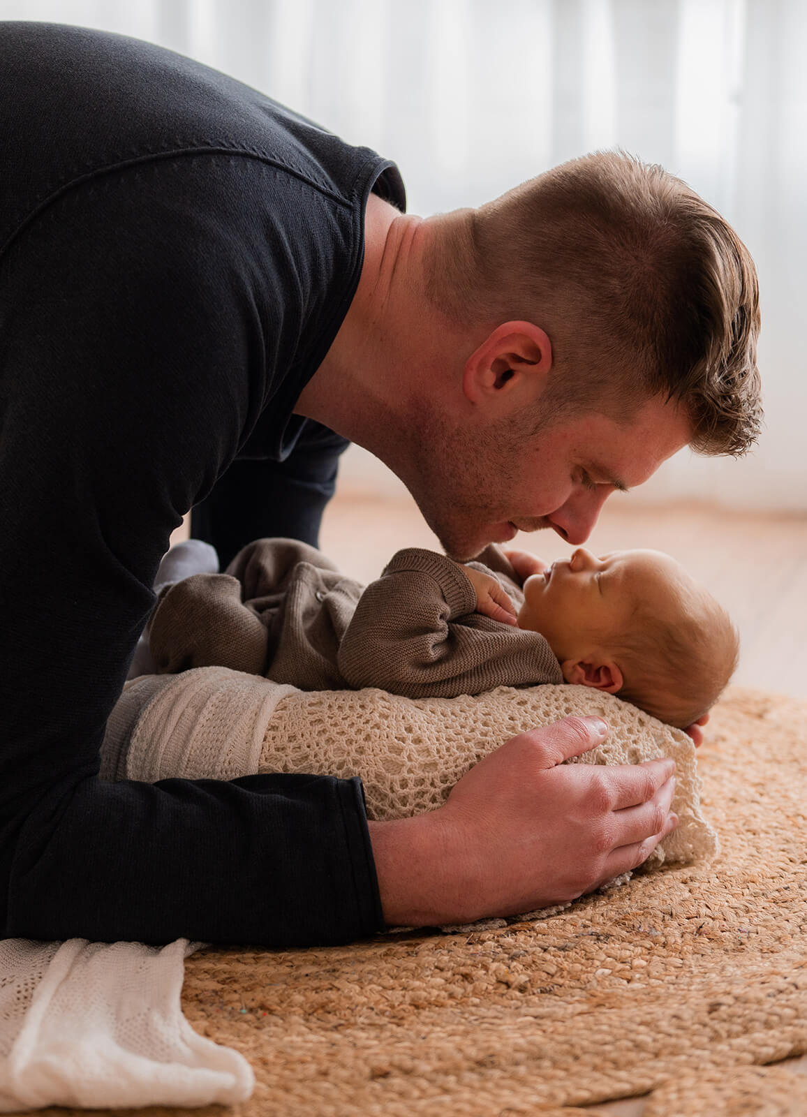 Papa küsst liebevoll sein Baby im Bohofotostudio München