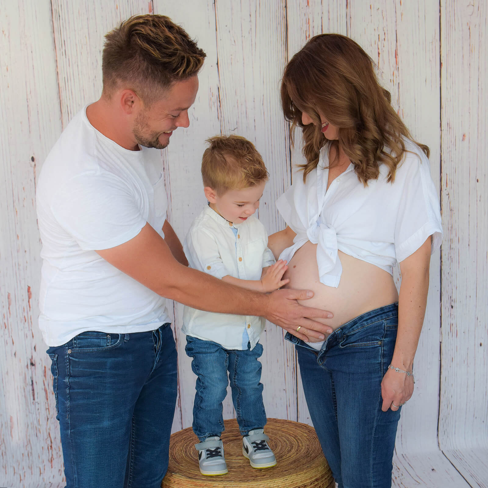 Papa und Bruder streicheln liebevoll über den Babybauch