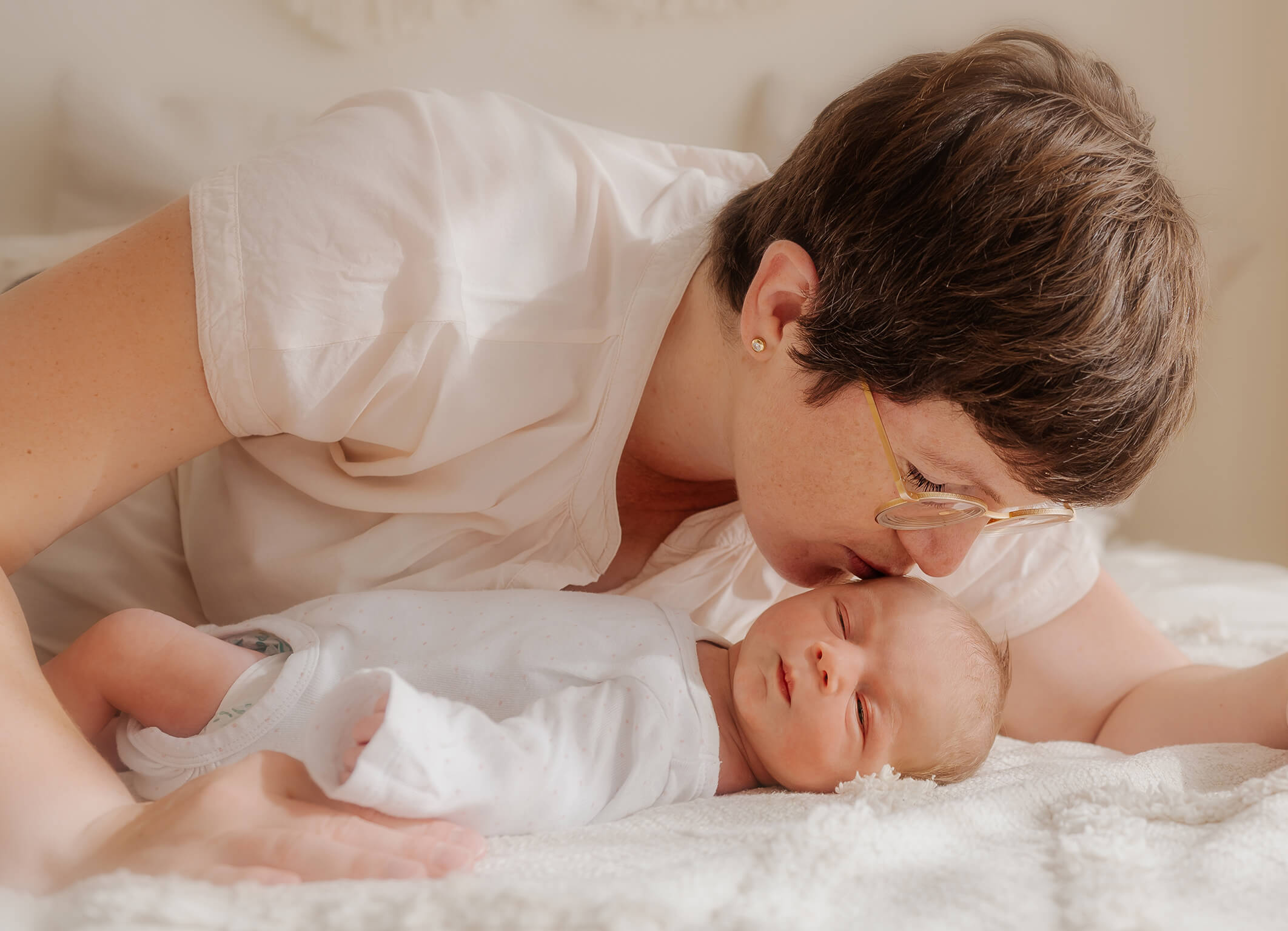 Mama küsst liebevoll ihr Neugeborenes Baby