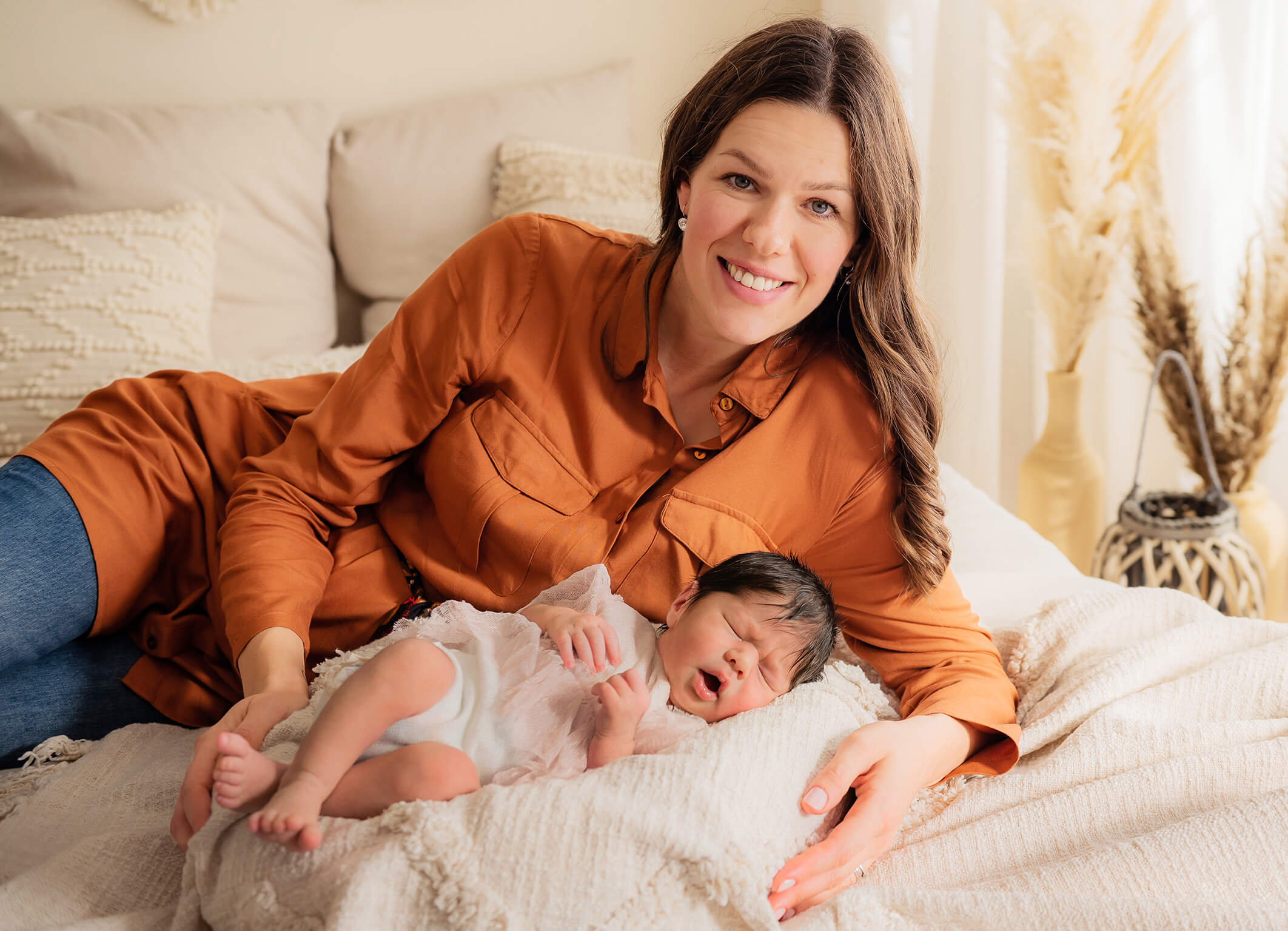 Mama mit Neugeborenem Baby auf dem Bett im Fotostudio Trudering