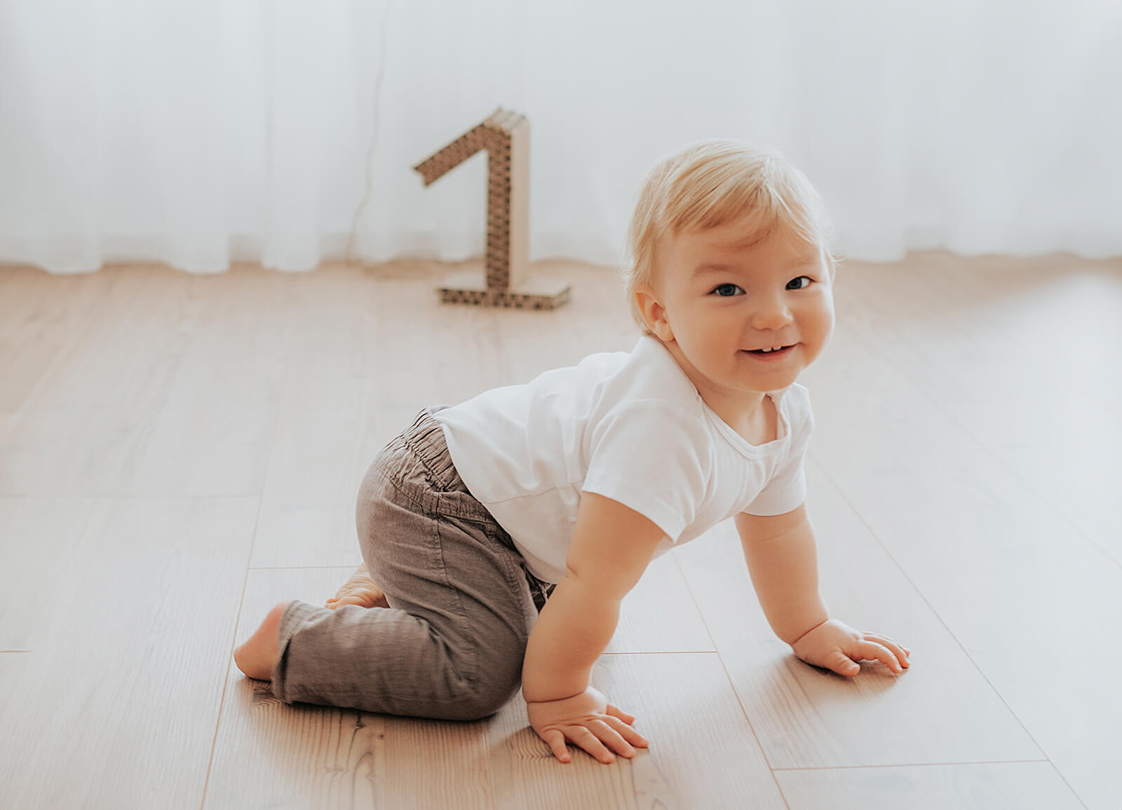 lachen und krabbeln beim ersten Fotoshooting zum Geburtstag im Tageslichtstudio München